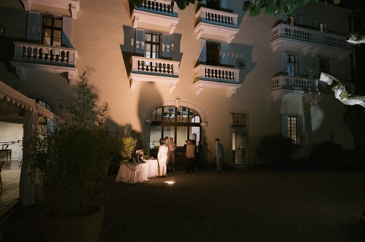 Lit abbey facade with stacked balconies above a candlelit courtyard at Abbaye de Talloires