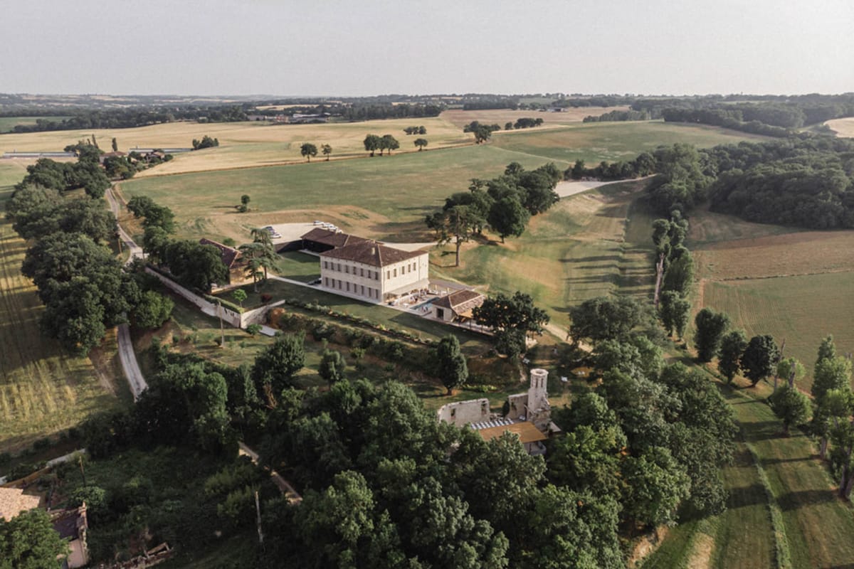 Aerial drone view of French country estate with manor house, barn, and surrounding fields