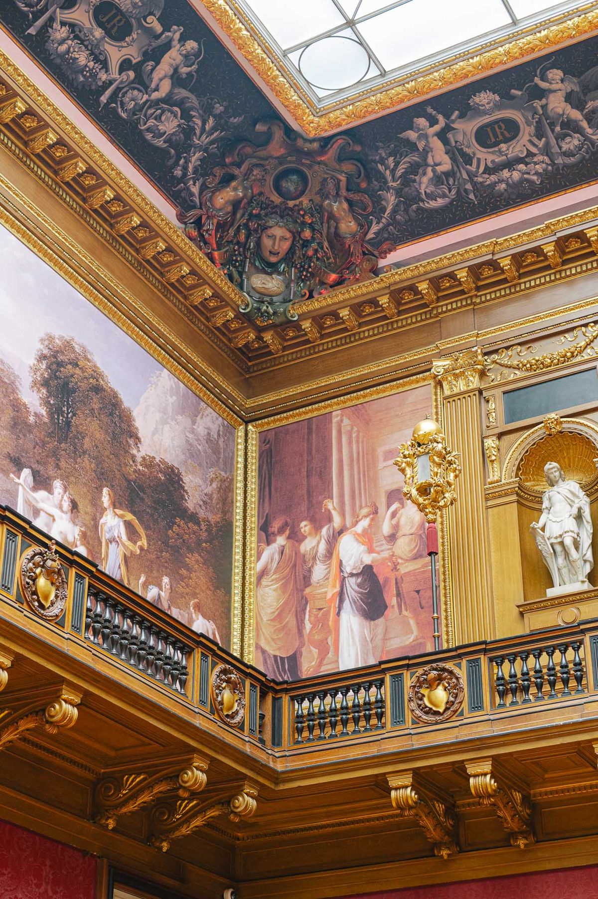 Ornate Belle Epoque interior with gilded balcony, classical paintings, cherub cornice, and glass skylight