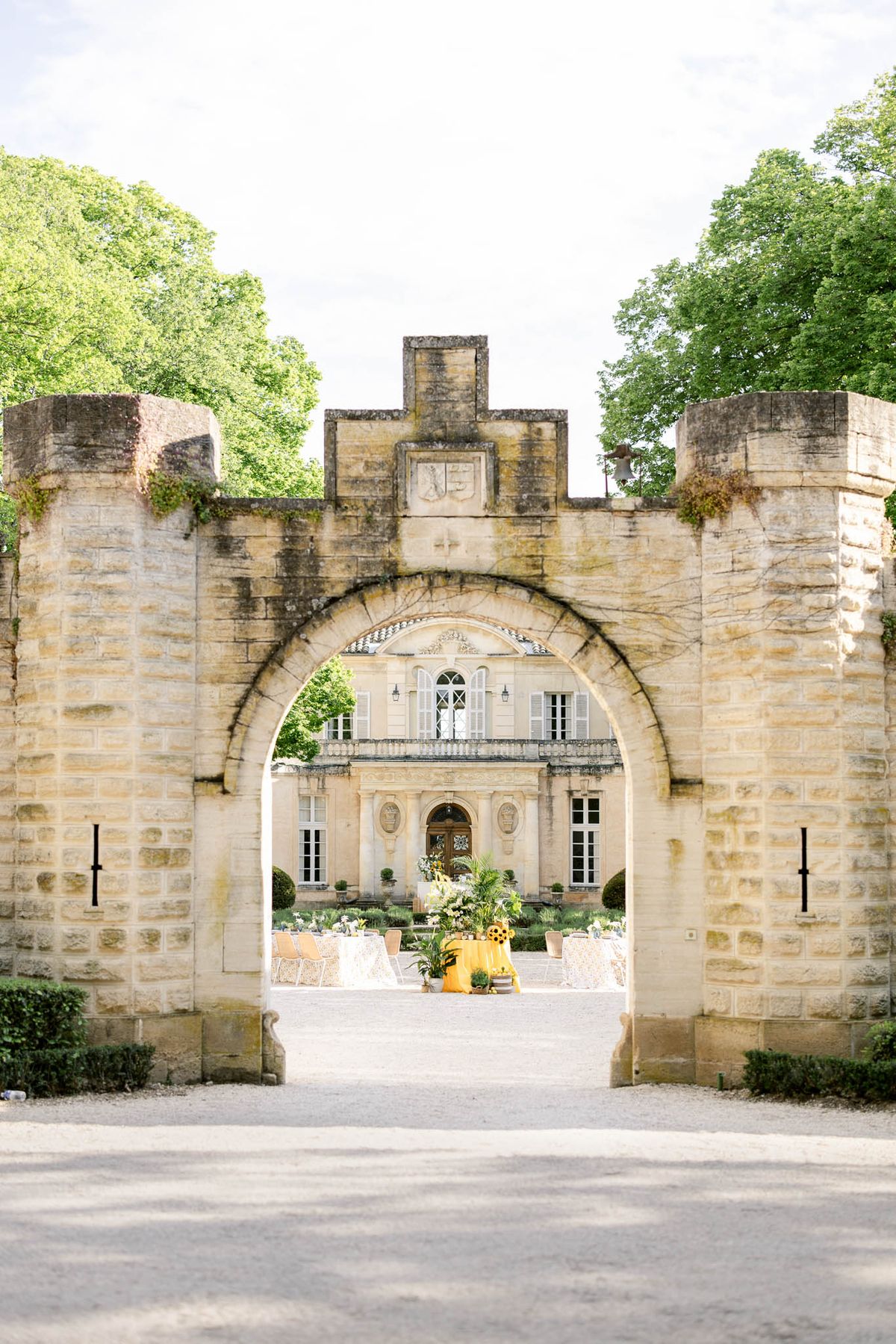 Yellow-themed cocktail setup with tropical palm arrangements framed through stone archway at French chateau