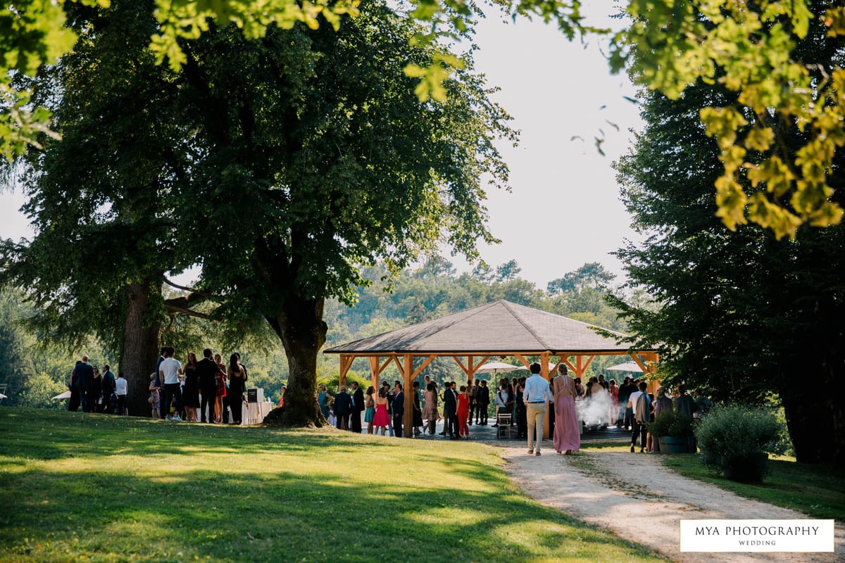 Elevated wide view of guests mingling under a timber pavilion on the grounds of a French country estate