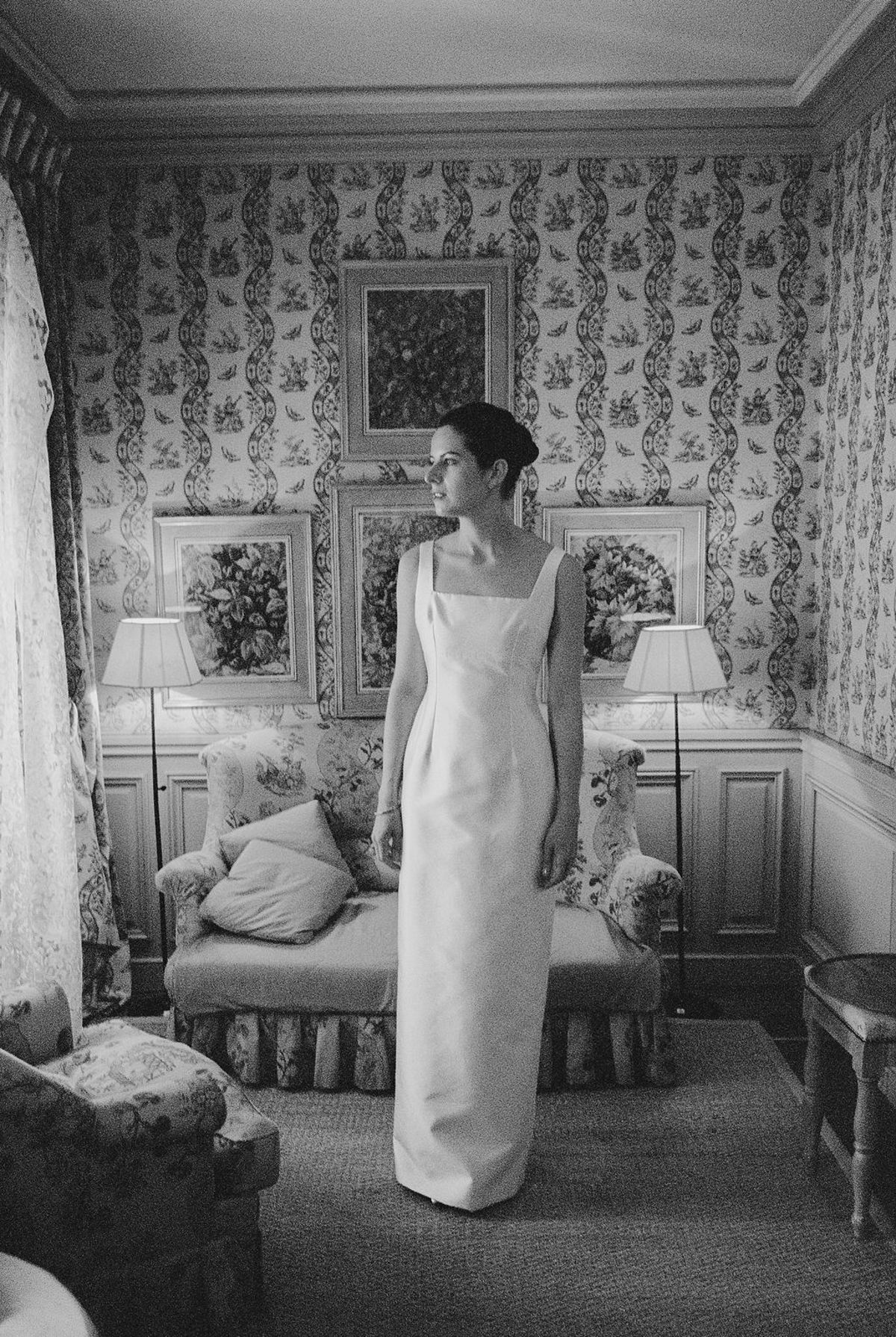 Bride in silk column dress in toile-papered chateau bedroom