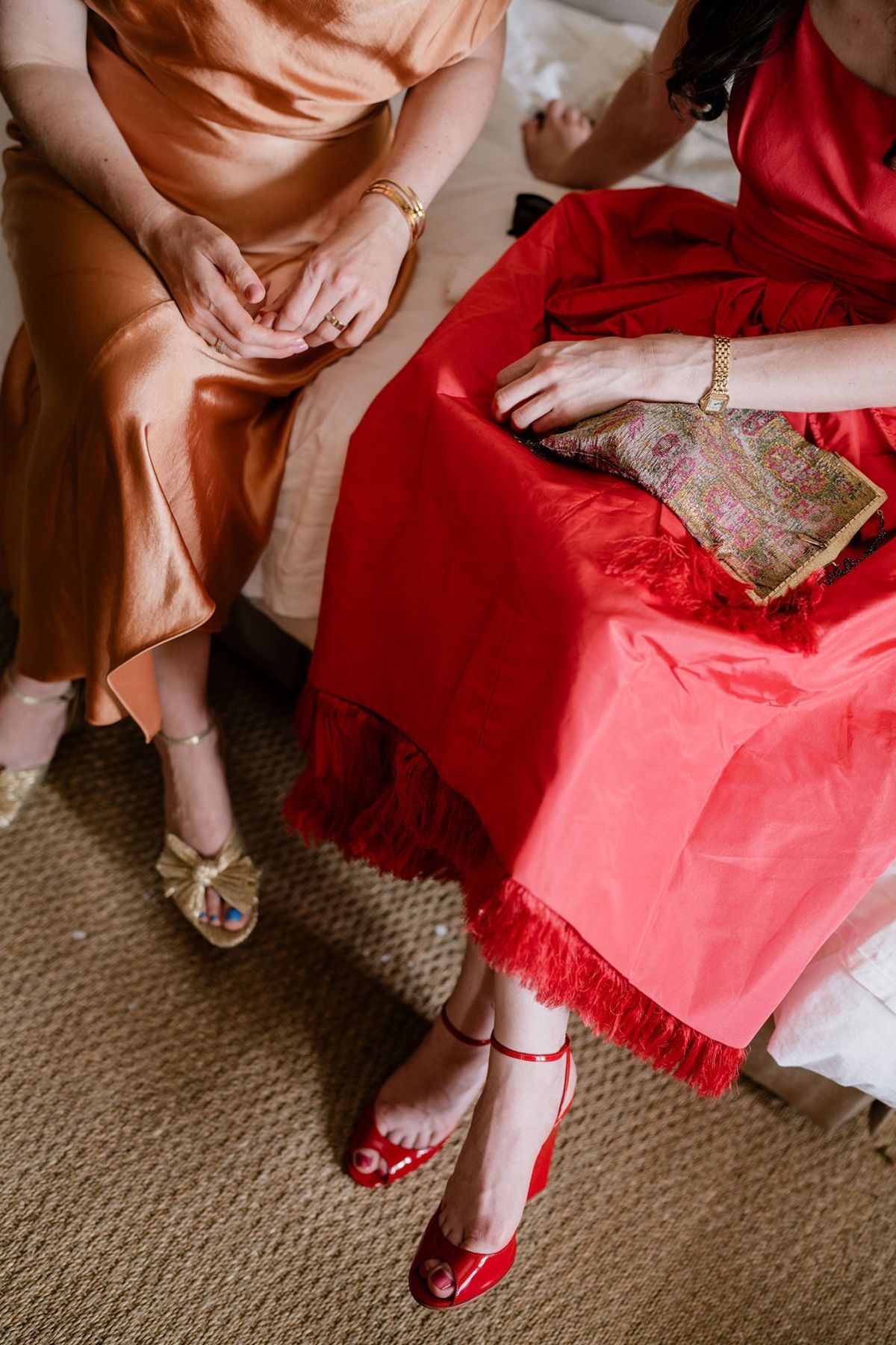 Overhead of bridesmaids in copper and coral gowns with gold heels and beaded clutch
