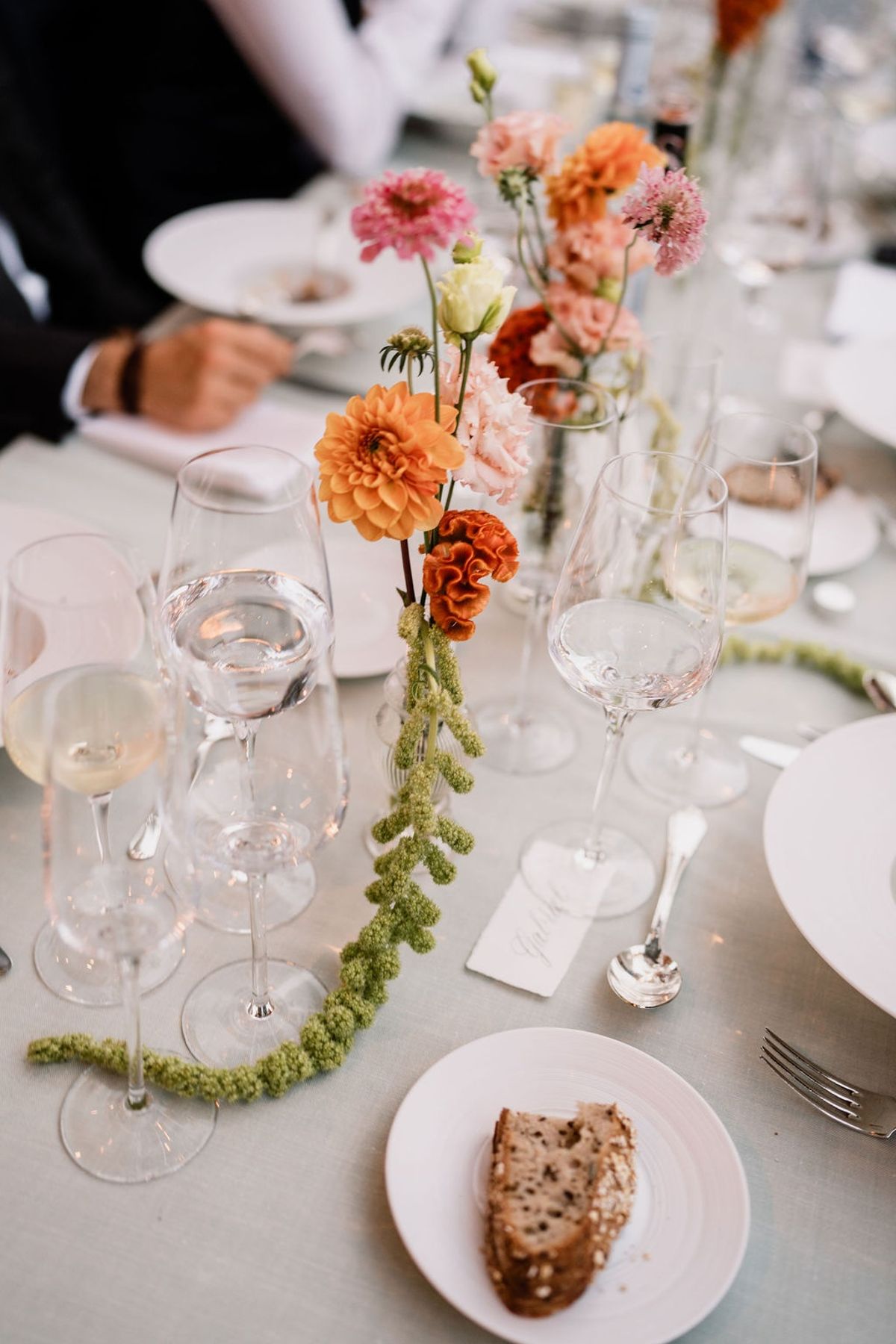 Tablescape with bud-vase pink and orange florals stemmed glasses and bread plate