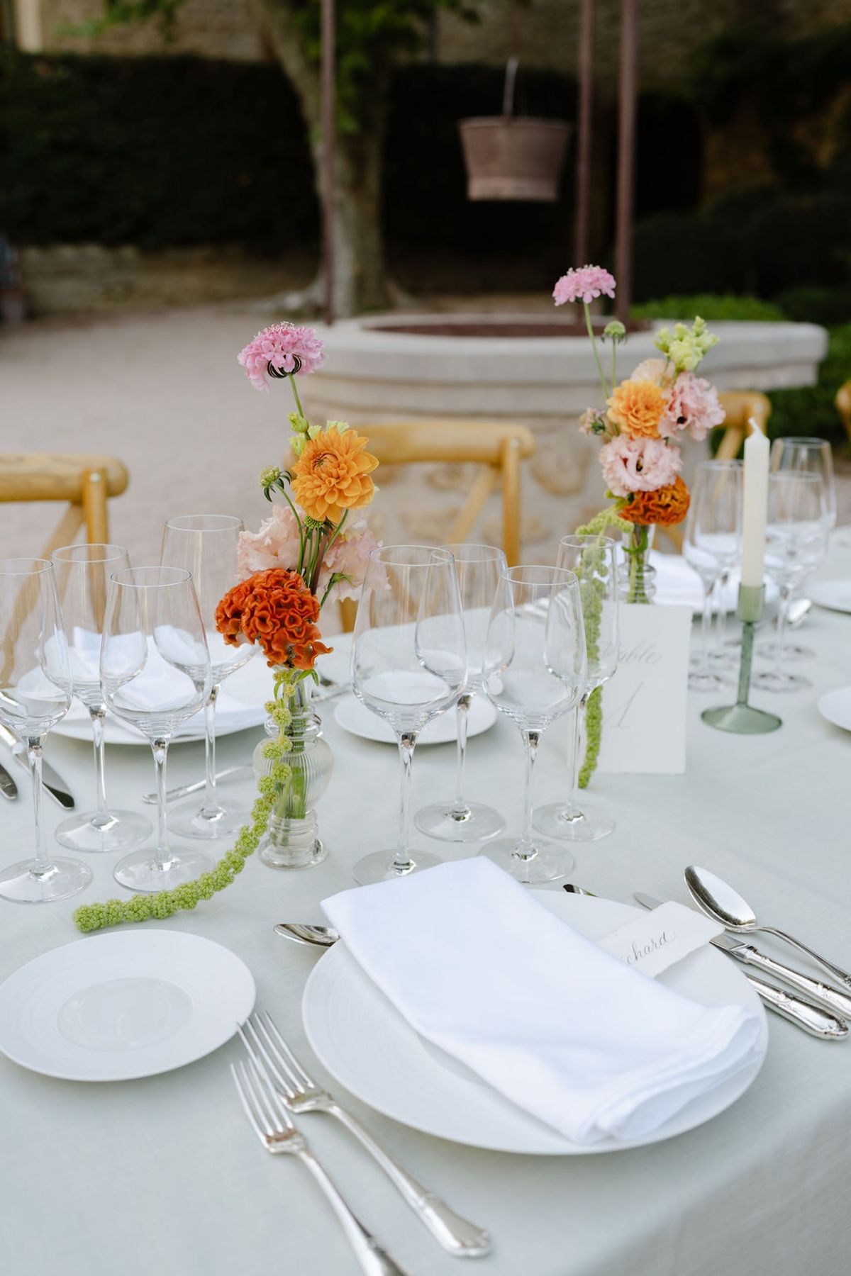 Place setting with sage linen white porcelain silverware and pink coral florals