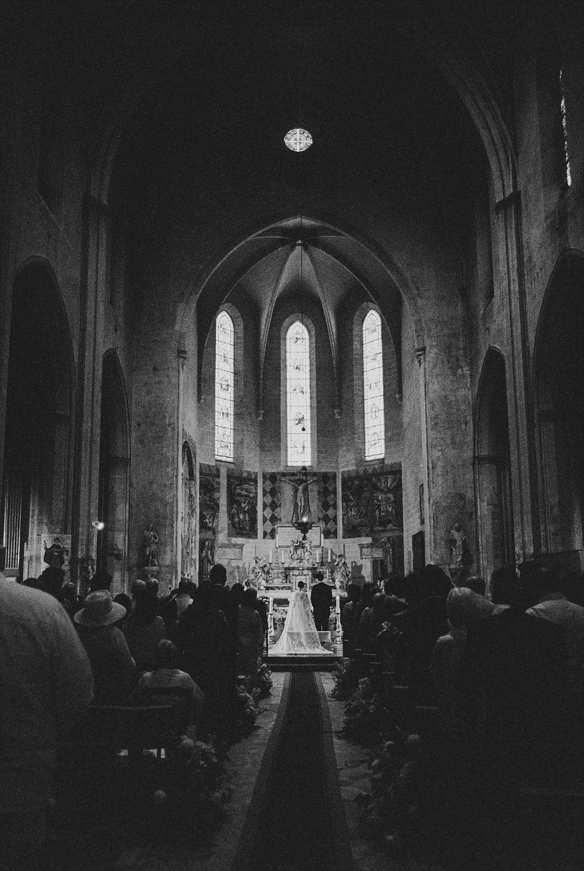 Couple at medieval church altar with priest and witnesses under stained glass