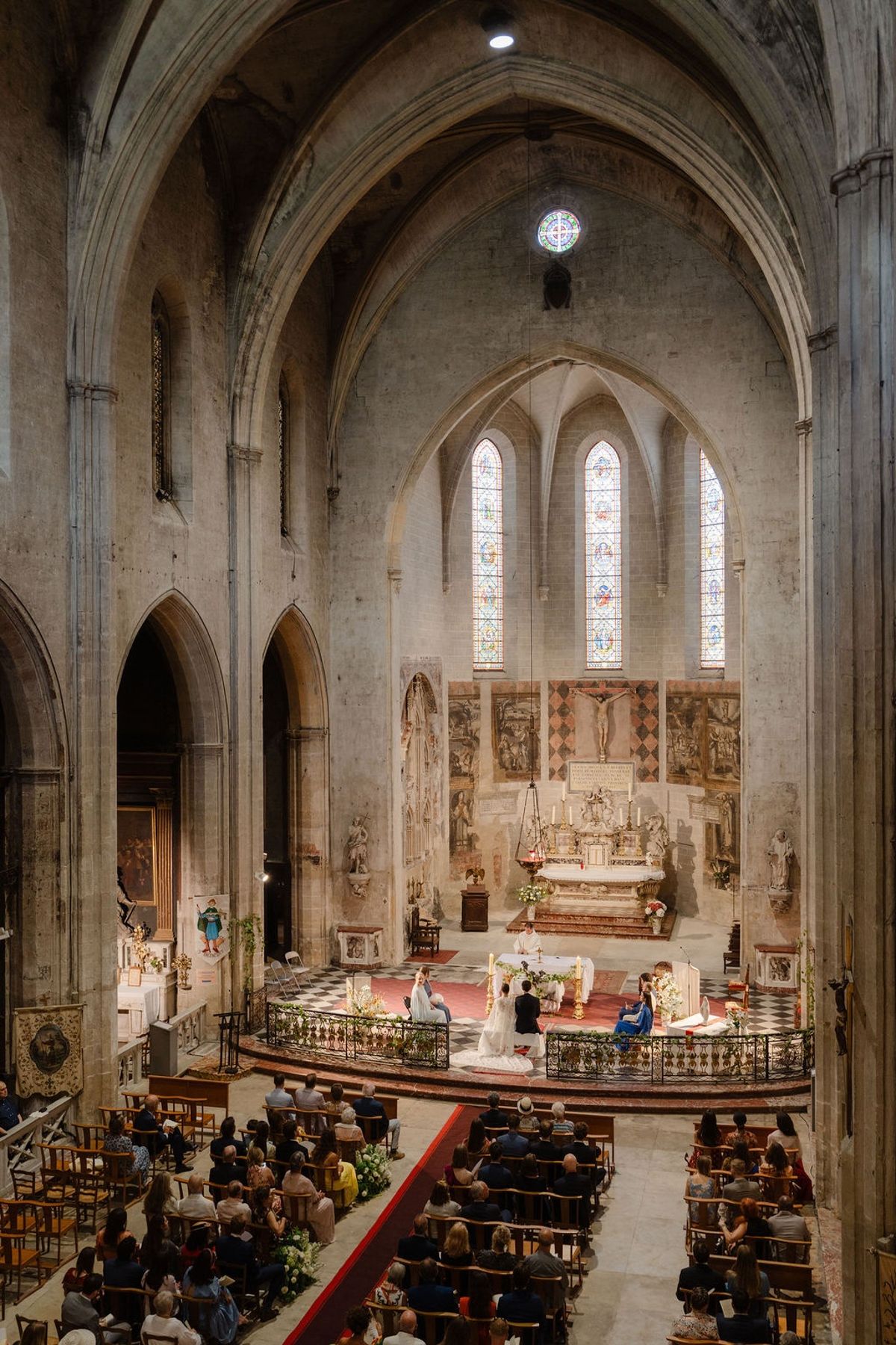 Wide elevated view of medieval church ceremony with guests seated in wooden pews