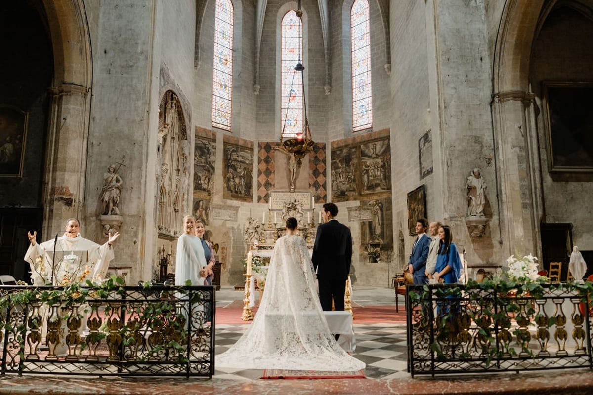 Couple at chapel altar with priest cape trailing on chequerboard marble floor