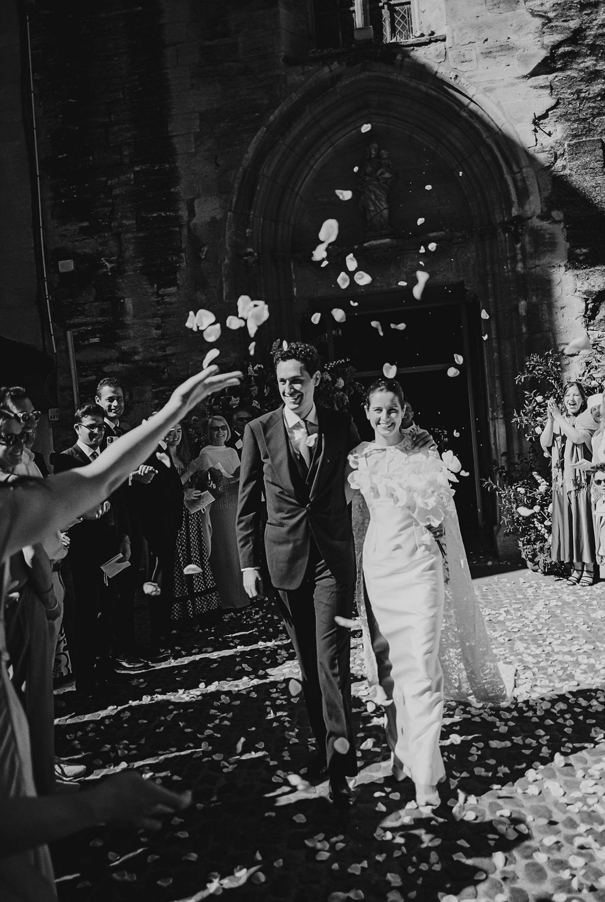 Black and white newlyweds walking from church doorway through petal toss