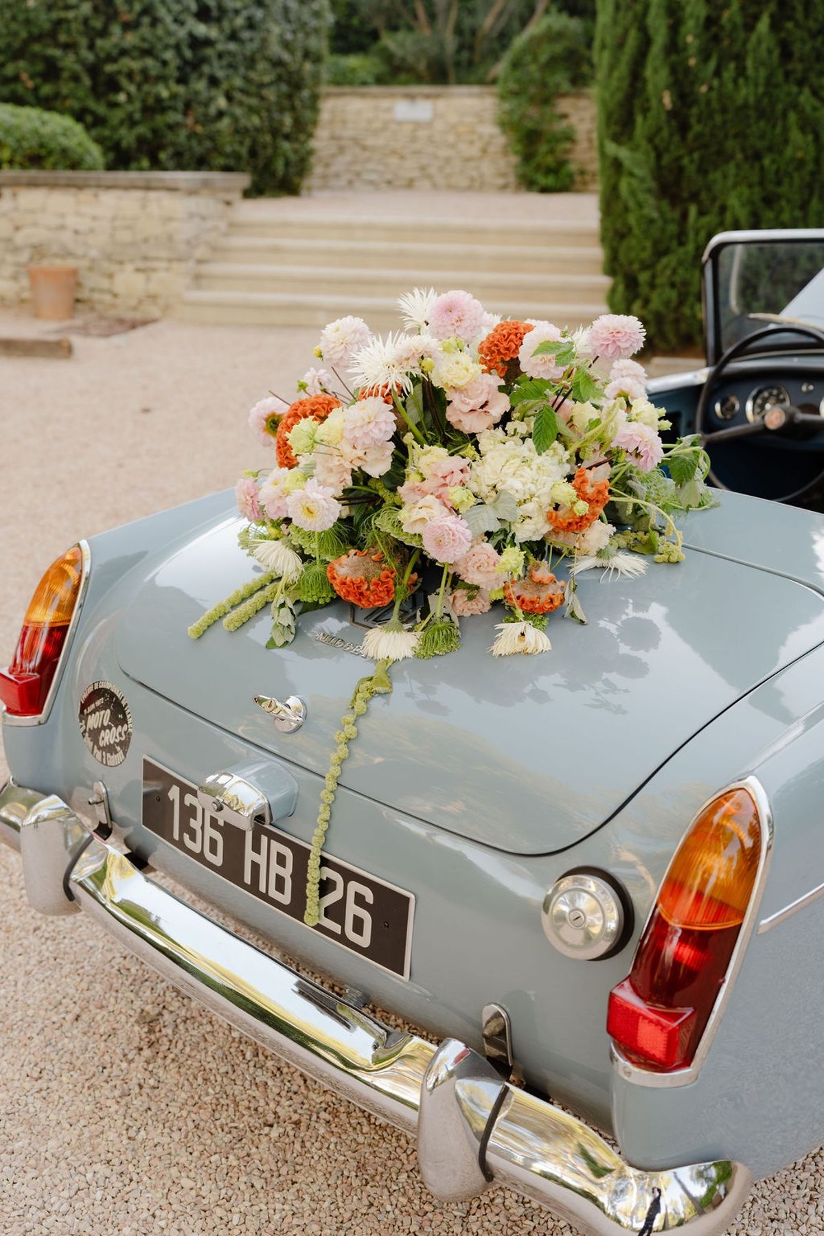 Blush and coral floral arrangement on boot of powder-blue vintage convertible