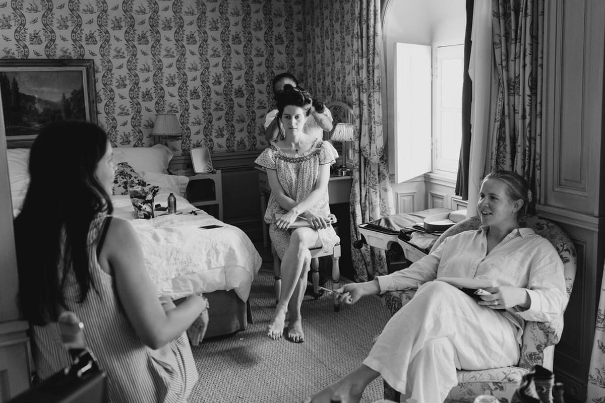 Black and white getting-ready scene with bridal party in chateau bedroom