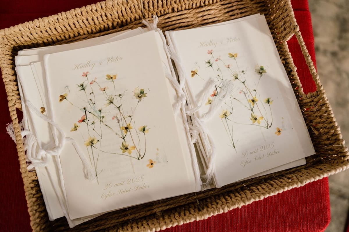 Woven basket of ribbon-tied ceremony booklets with watercolour wildflower covers