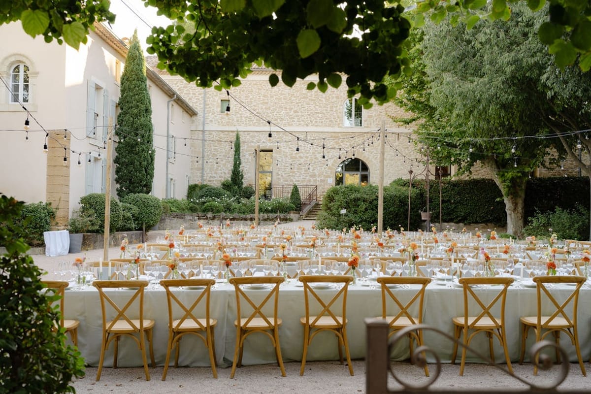 Wide elevated view of long banquet tables and bistro chairs in chateau courtyard