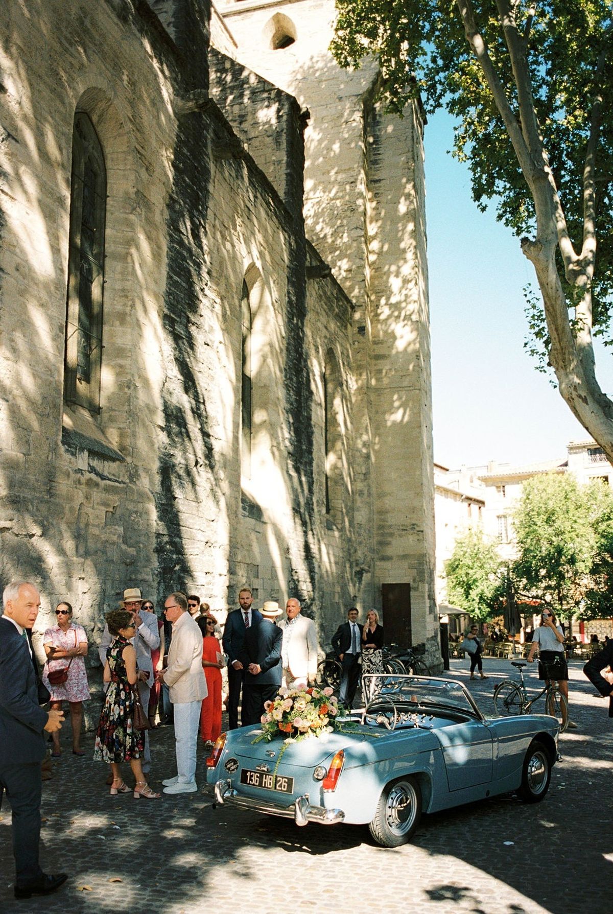 Powder-blue vintage convertible with blush florals waiting outside medieval church