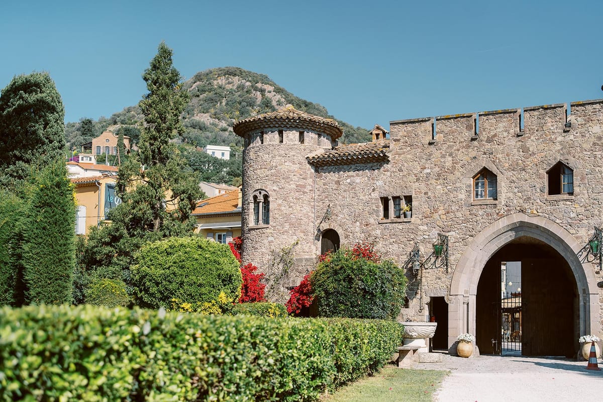 Medieval stone castle with round tower, crenellated battlements, and Gothic arched entrance gate