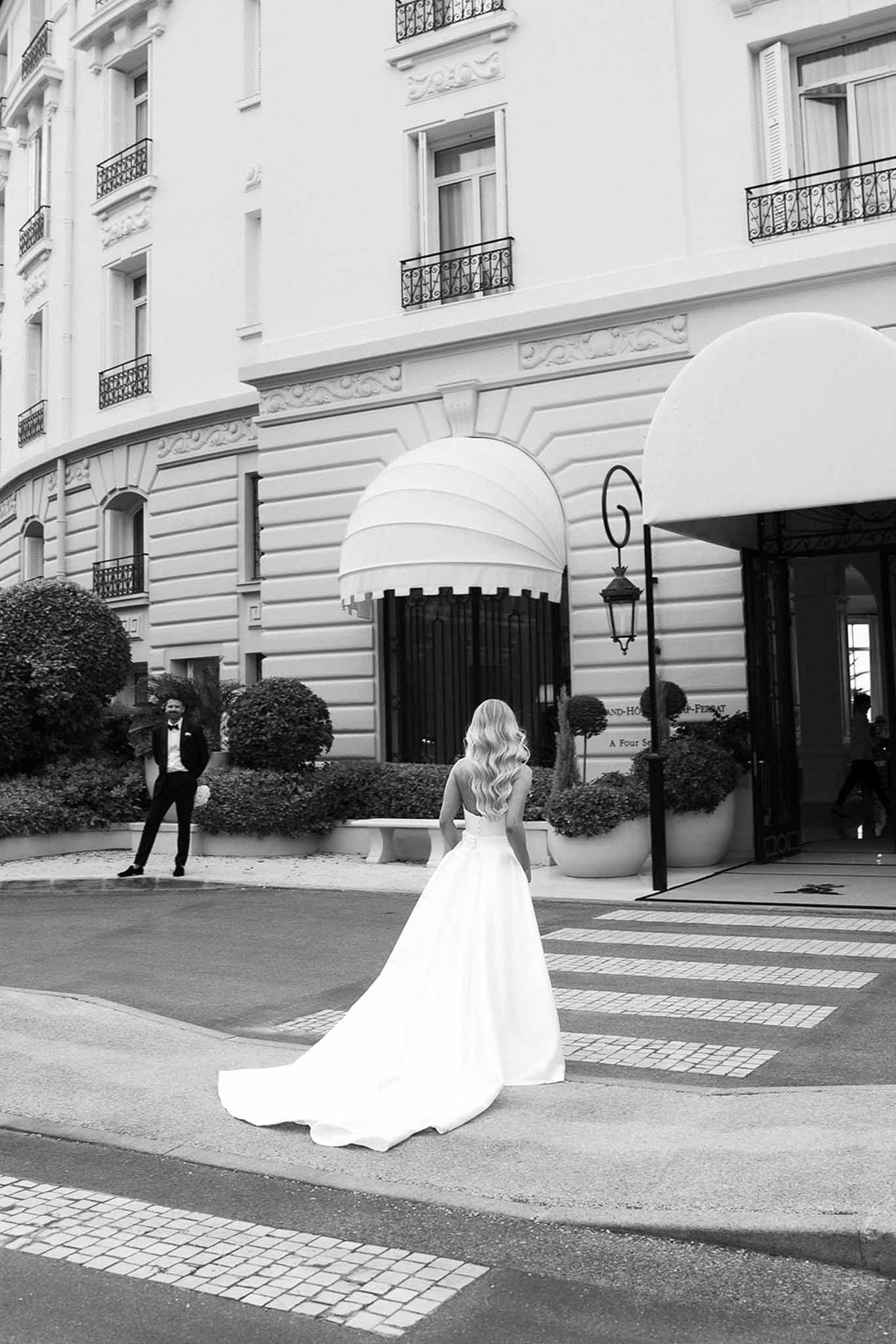 Black and white bride with cathedral train on crosswalk facing groom at Belle Epoque hotel with striped awnings