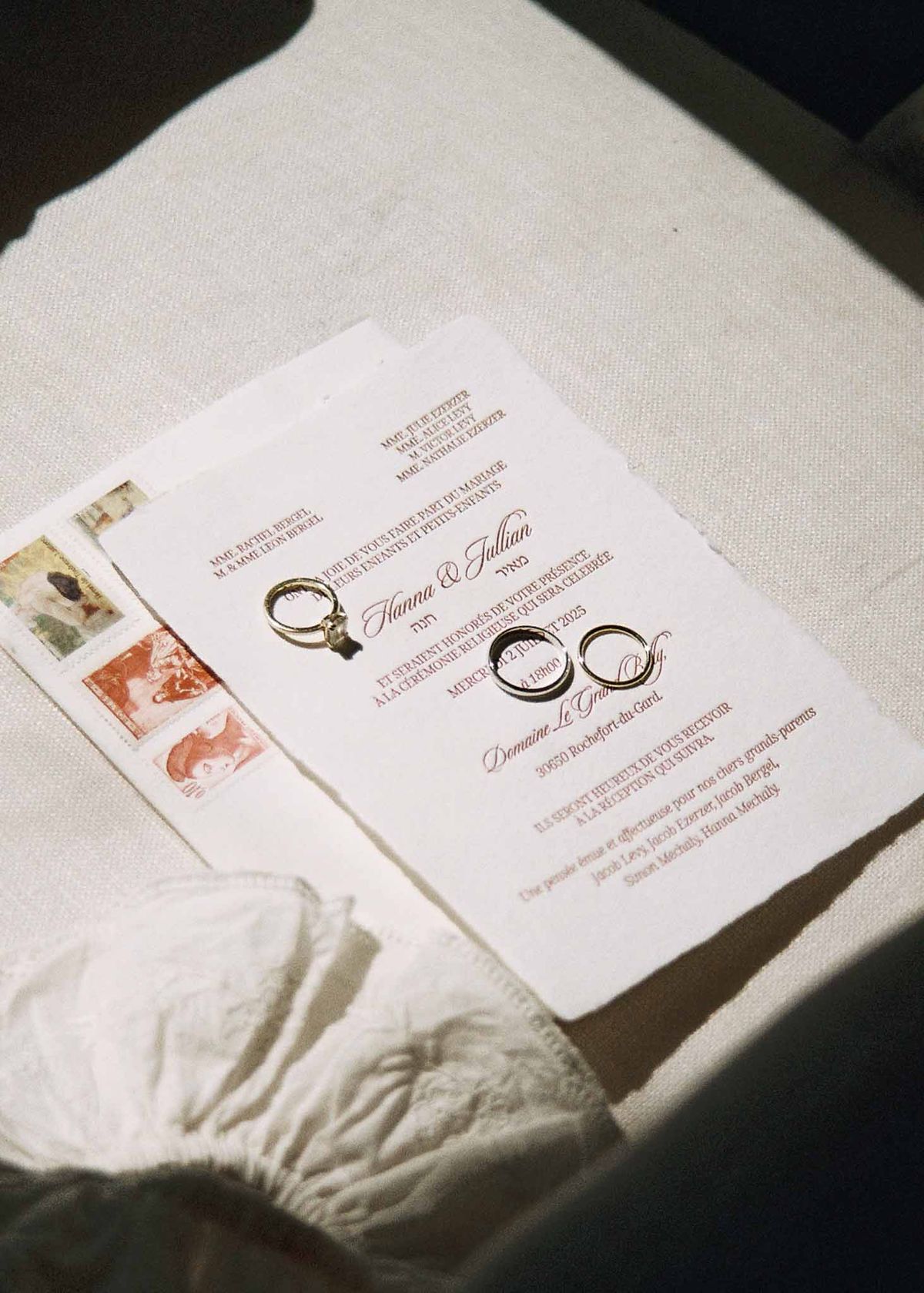 French wedding invitation on deckle-edge cream paper with gold bands, diamond ring, and vintage stamps