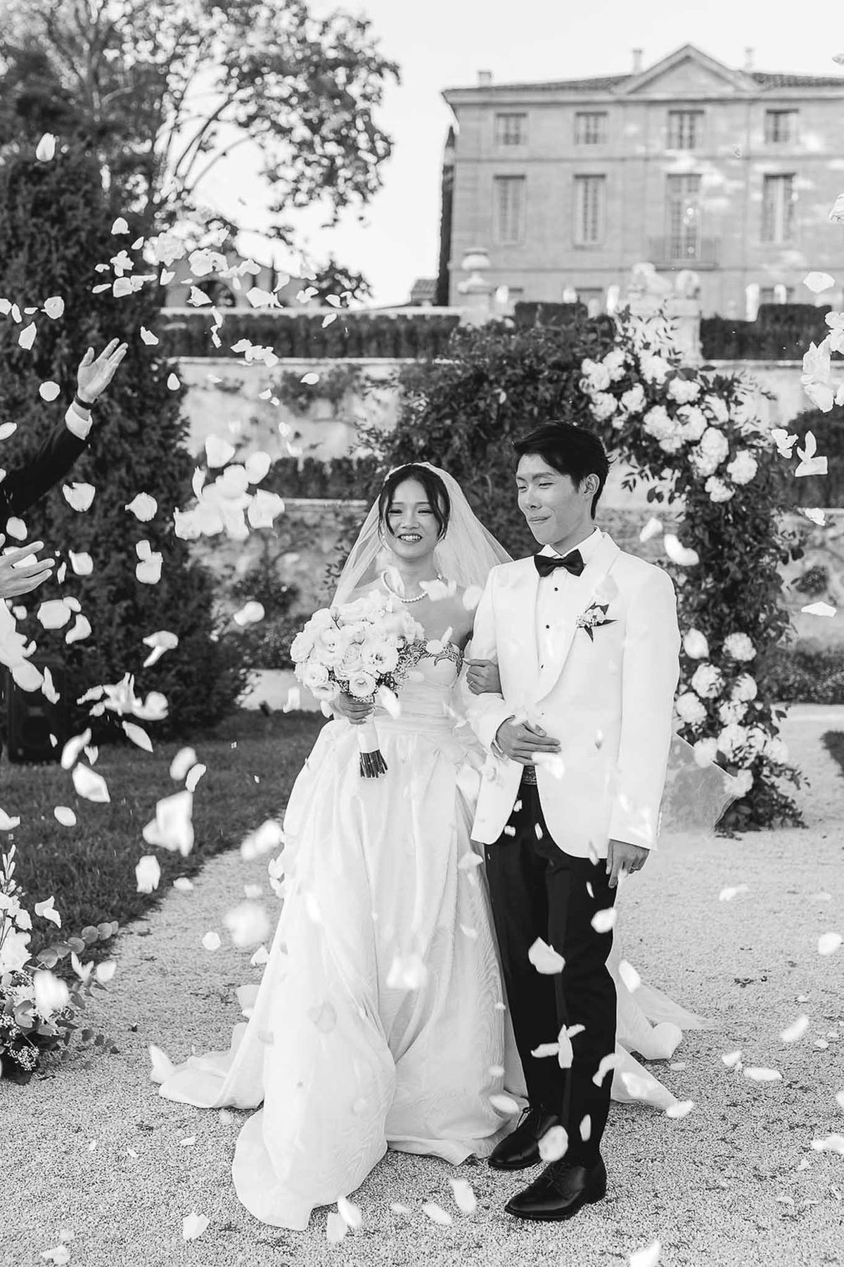 Couple laughing during petal toss after outdoor ceremony at Château de la Gaude