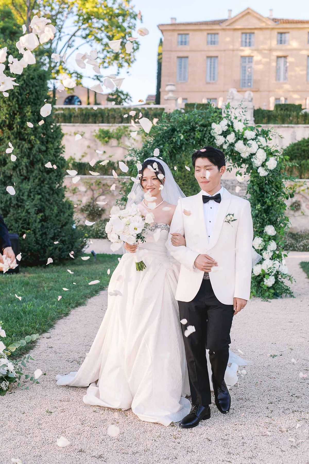 Bride and groom walking together after ceremony with petal confetti at Château de la Gaude
