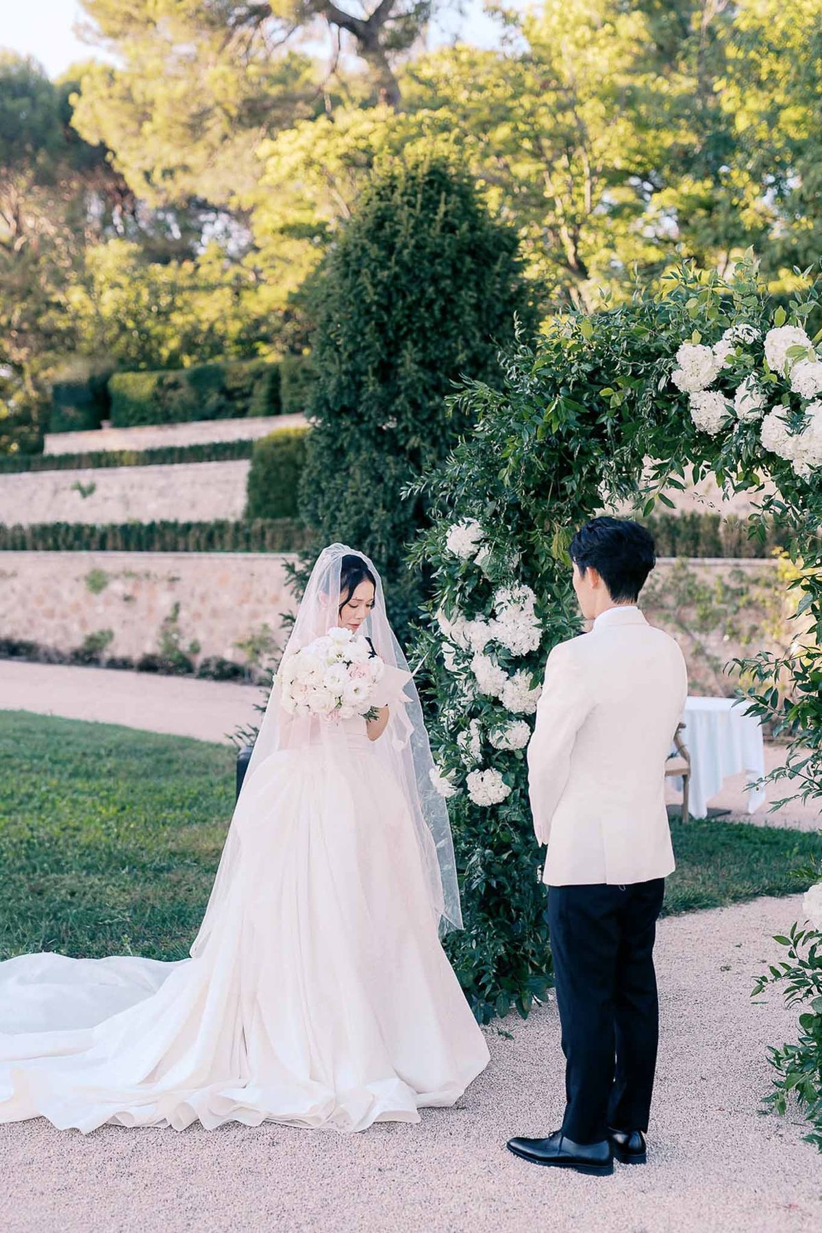 Couple exchanging vows under greenery arch at Château de la Gaude outdoor ceremony