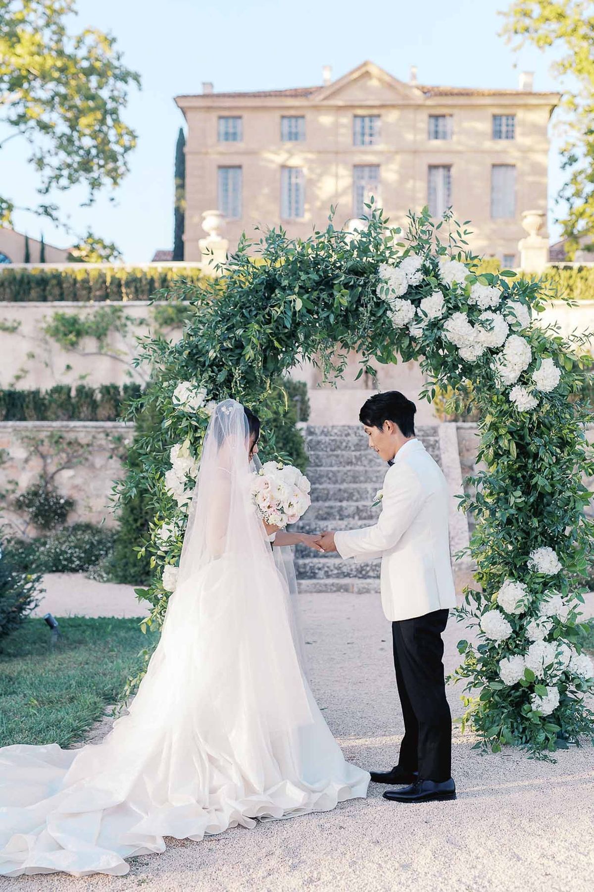 Groom placing ring on bride's finger during ceremony at Château de la Gaude