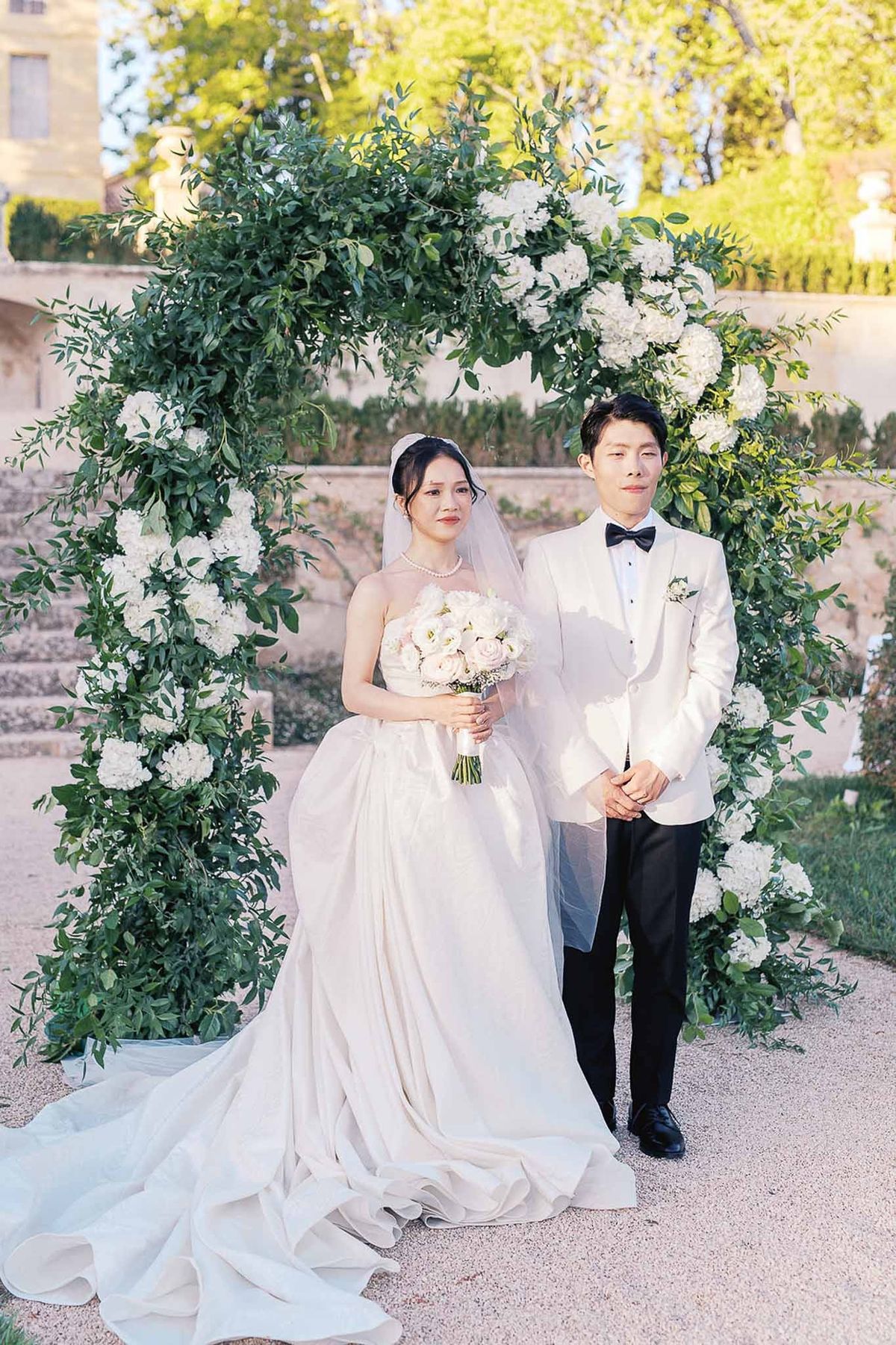 Bride and groom standing together under ceremony arch at Château de la Gaude