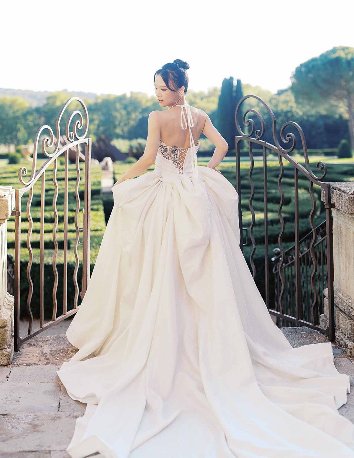 Detail of bride's open-back halter-neck gown at garden terrace at Château de la Gaude
