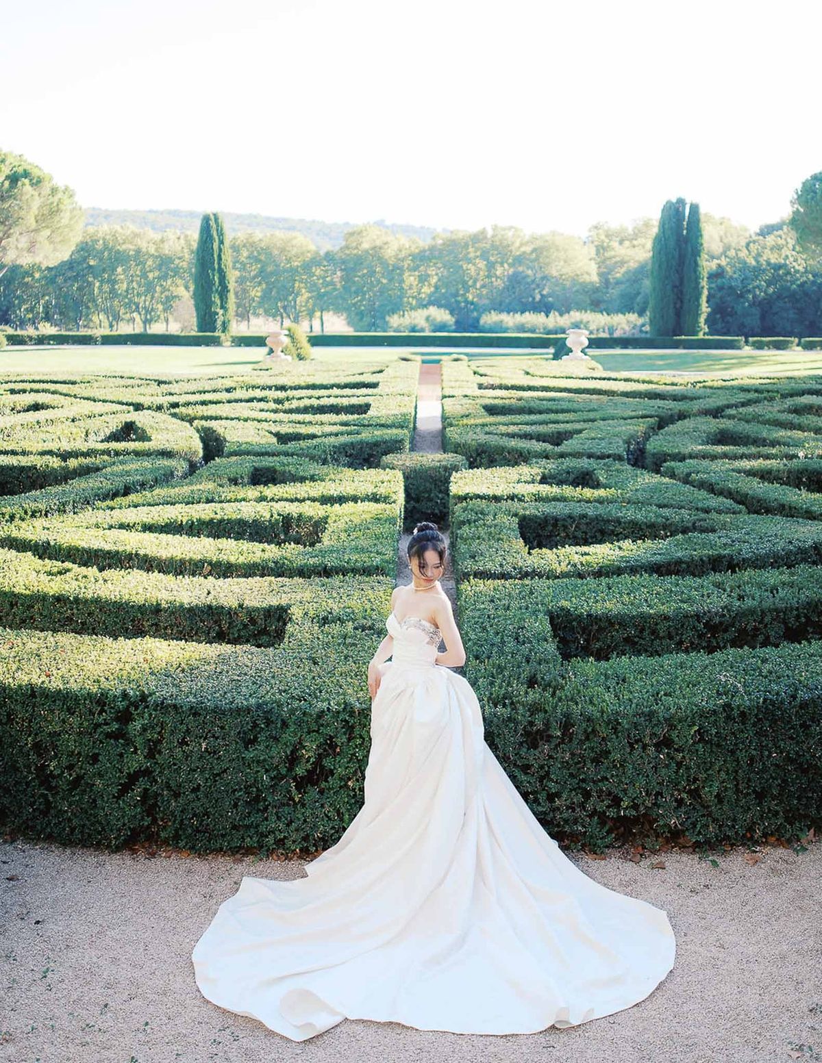 Bride walking through parterre maze garden in ball gown at Château de la Gaude