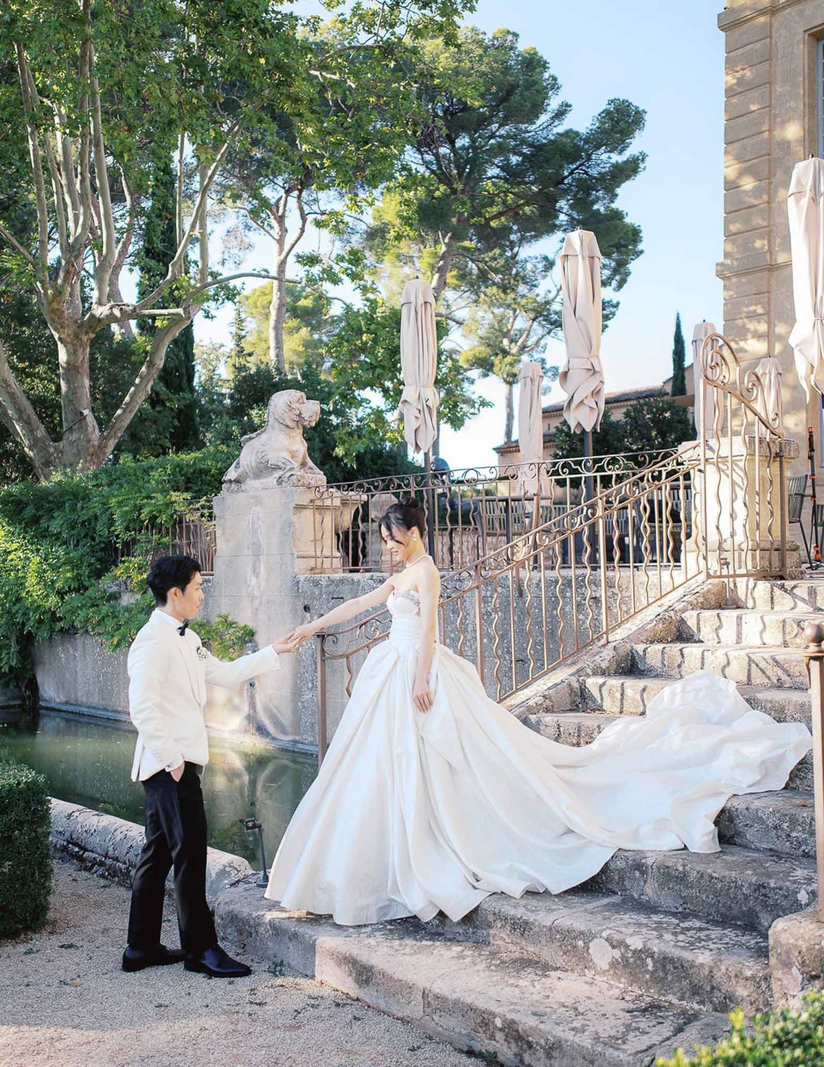 Groom holding bride's hand during first look on stone steps at Château de la Gaude