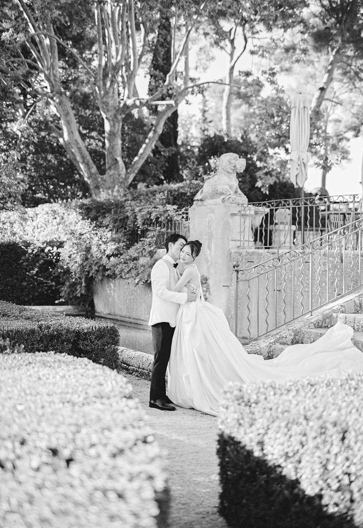 Groom kissing bride on cheek during first look in château garden at Château de la Gaude