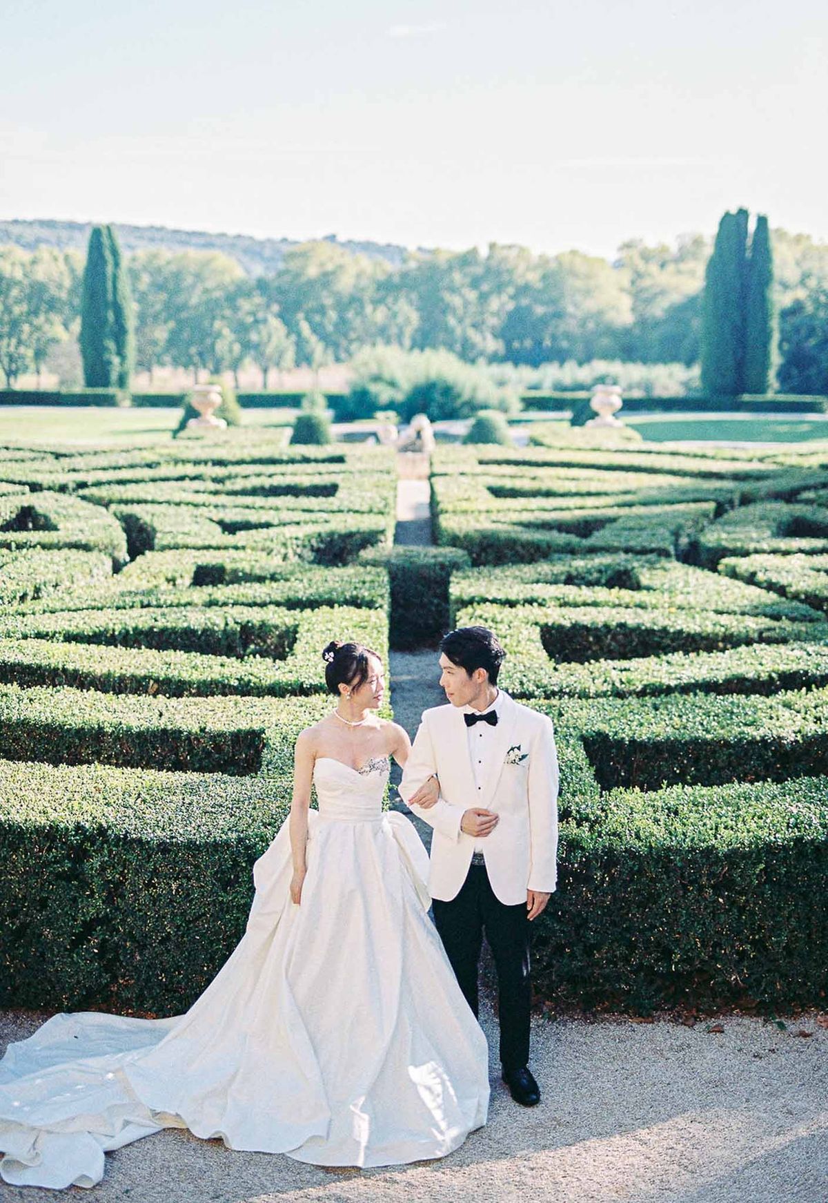 Bride and groom walking through parterre maze gardens at Château de la Gaude