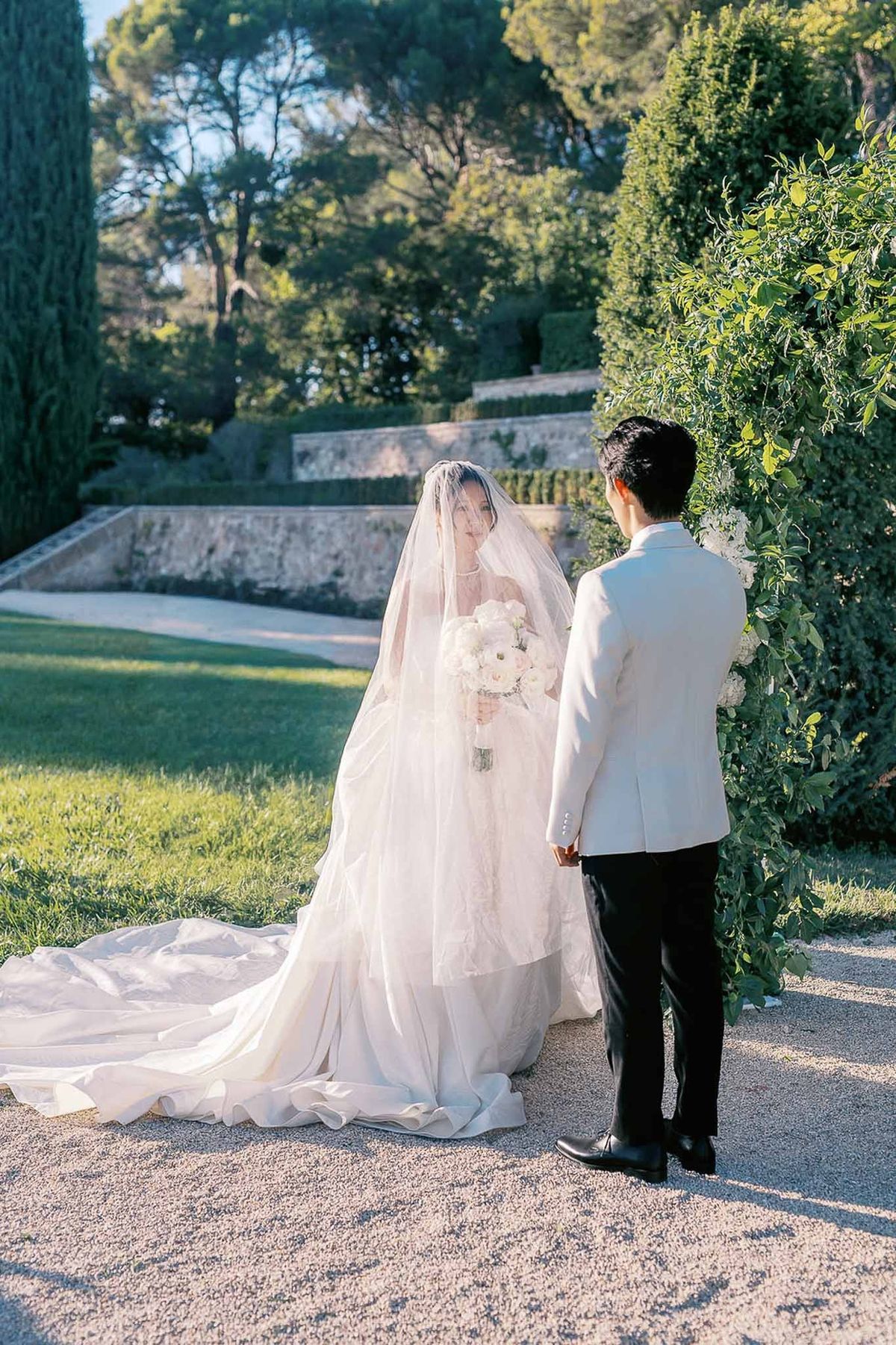 Couple holding hands at ceremony altar with veil trailing at Château de la Gaude