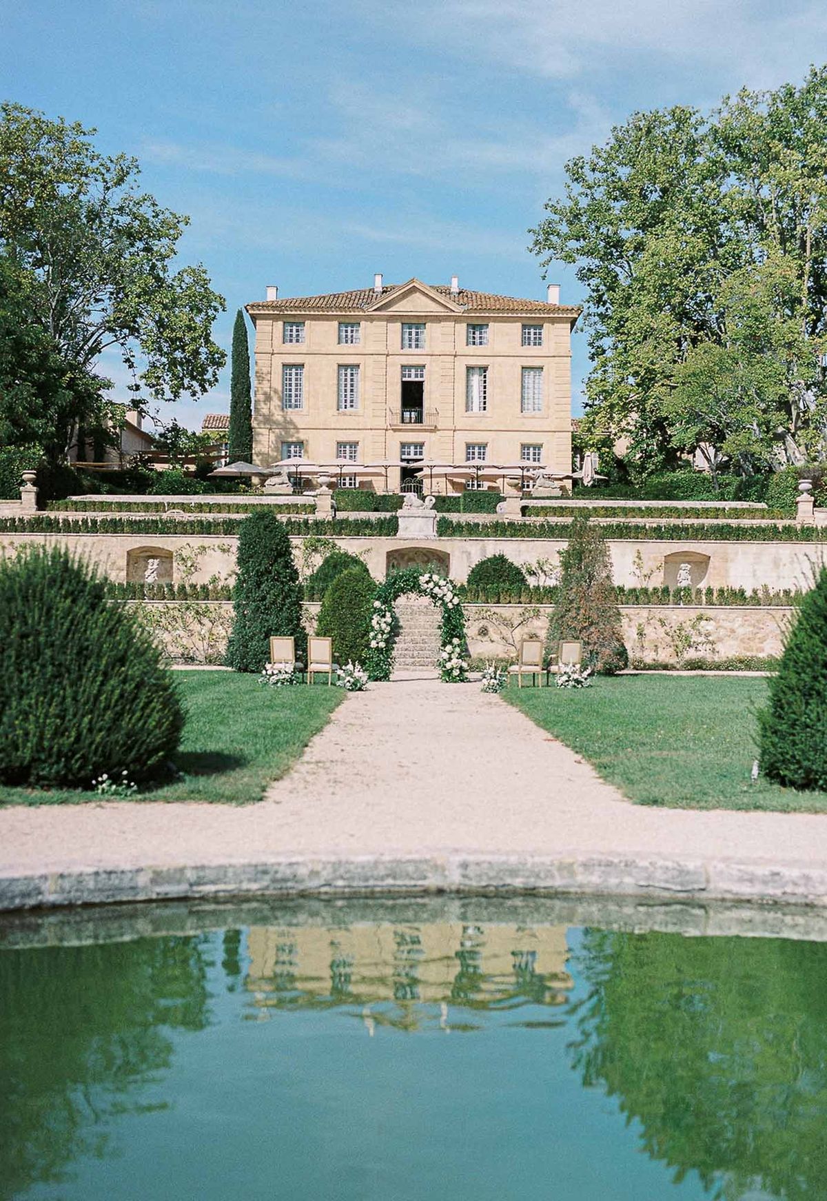 Château de la Gaude reflected in garden pond with ceremony arch in the distance