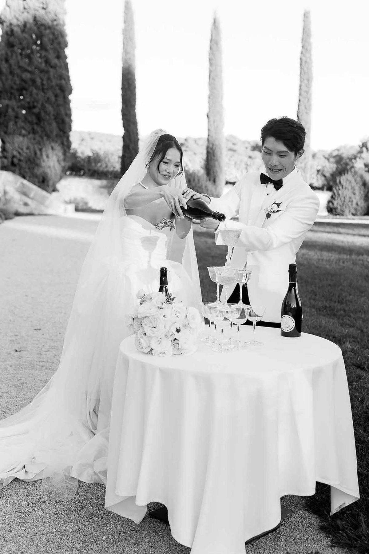 Couple pouring champagne together at outdoor reception at Château de la Gaude