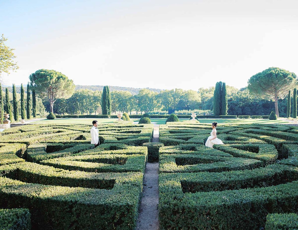 Bride and groom walking through parterre maze garden at Château de la Gaude