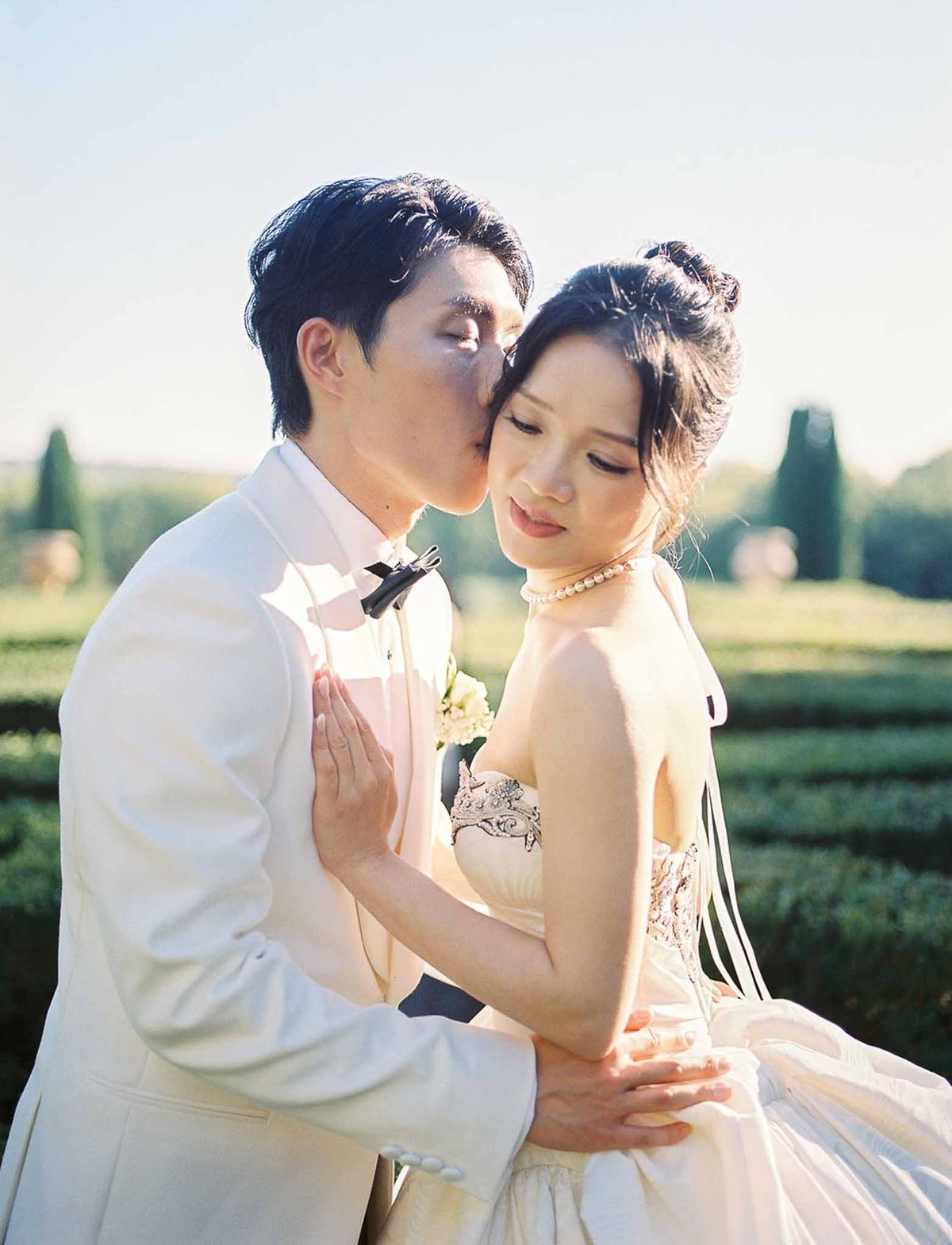 Groom kissing bride's forehead in golden hour light at Château de la Gaude
