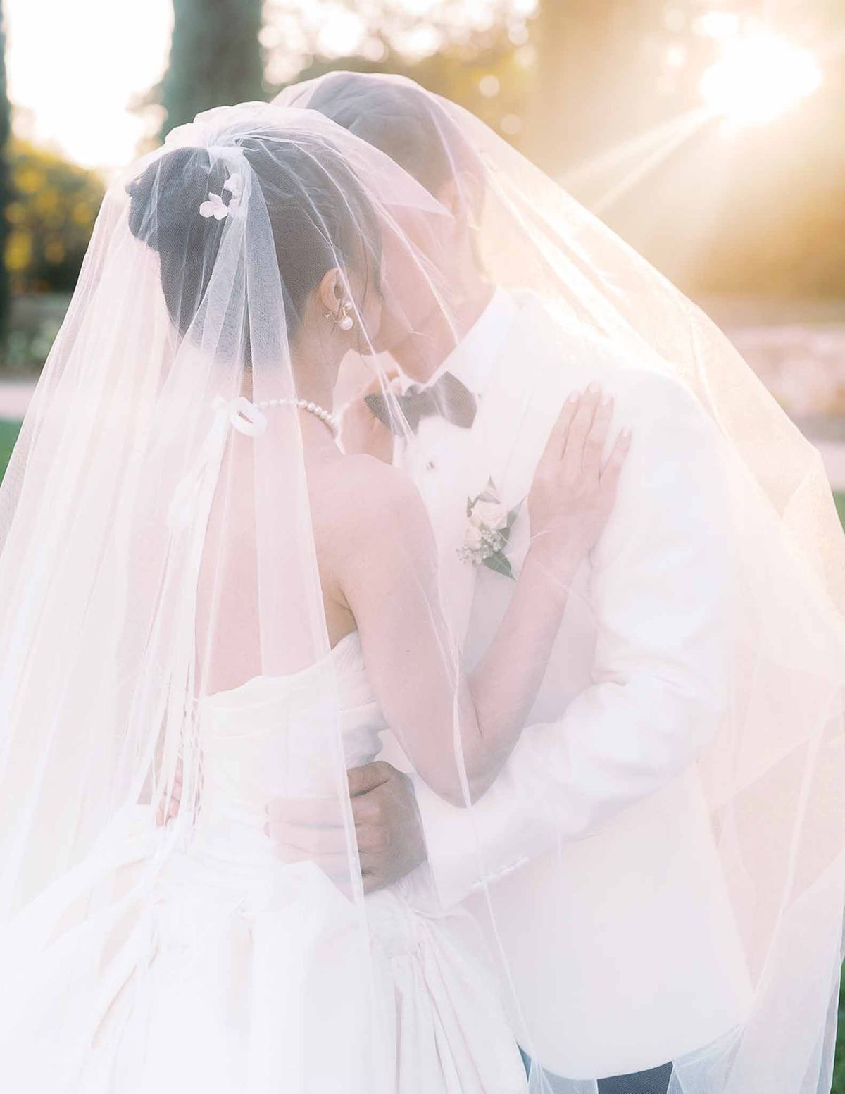 Couple kissing under veil with golden sunset light at Château de la Gaude