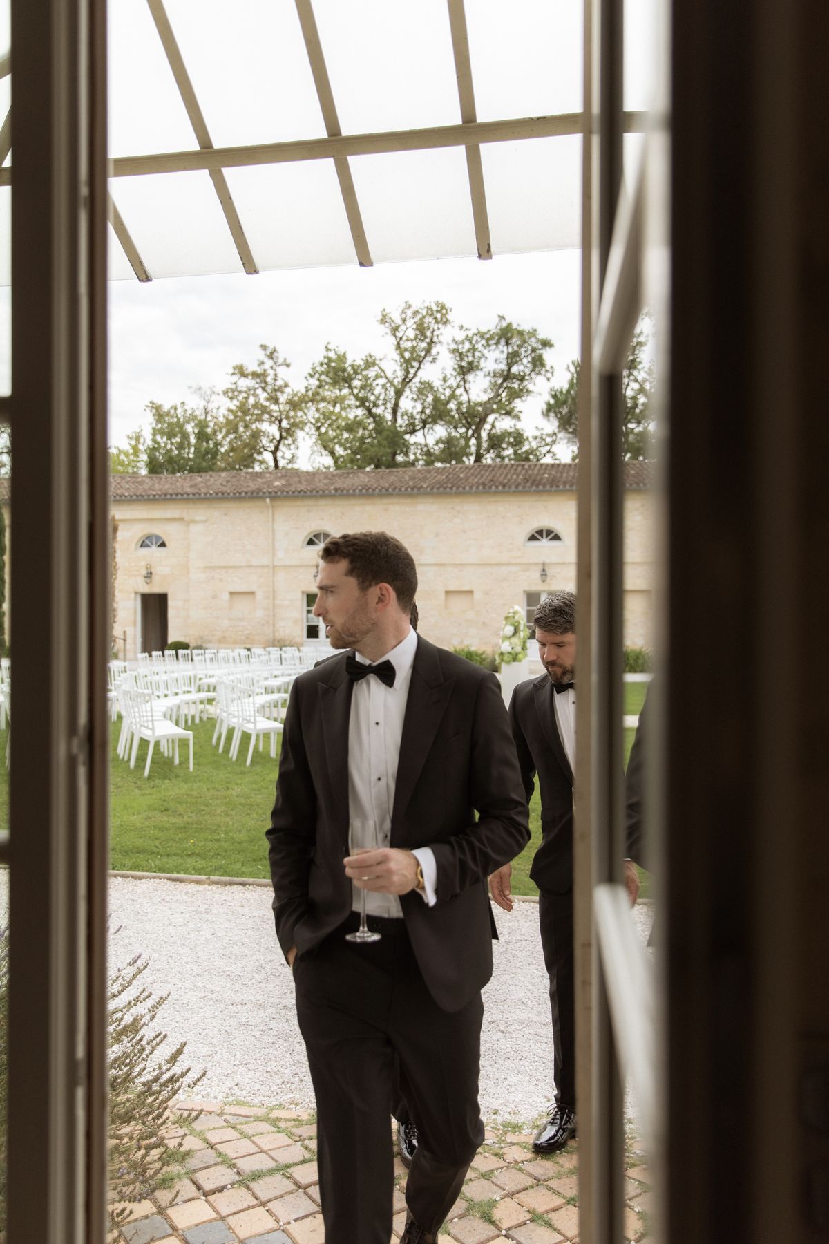 Groom walking into the courtyard before the ceremony at Chateau Gassies, Nouvelle-Aquitaine