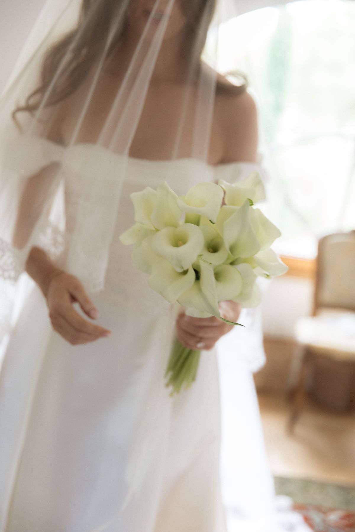 Bride beneath a veil holding a calla lily bouquet at Chateau Gassies, Nouvelle-Aquitaine