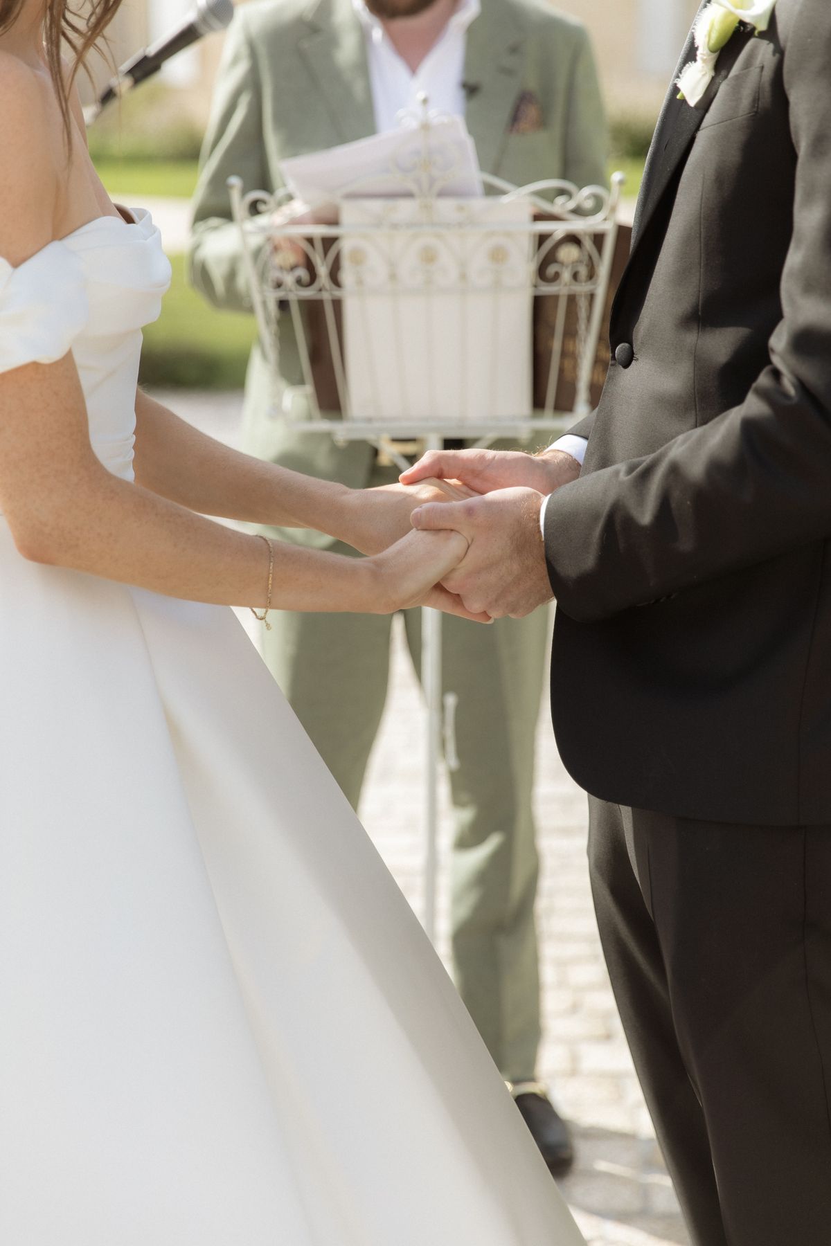 Bride and groom joining hands during the vows at Chateau Gassies, Nouvelle-Aquitaine