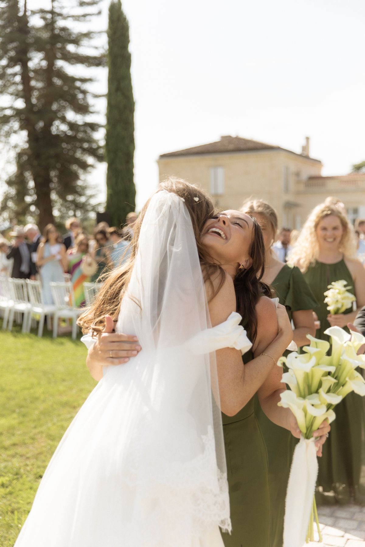 Bride hugging a bridesmaid after the ceremony at Chateau Gassies, Nouvelle-Aquitaine