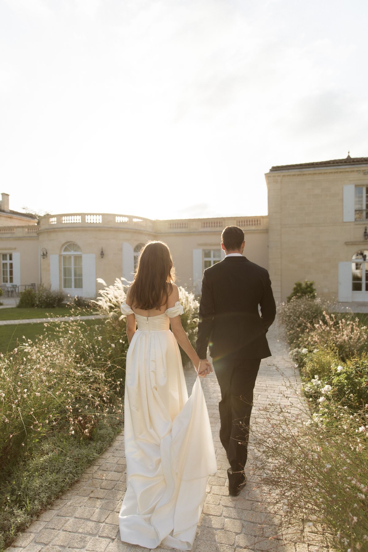 Bride and groom walking into golden hour at Chateau Gassies, Nouvelle-Aquitaine