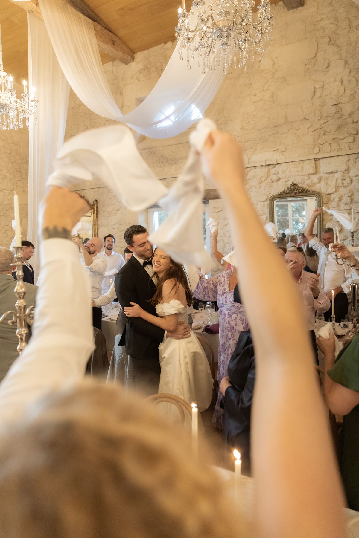 Couple embrace among napkin-waving guests at Chateau Gassies, Nouvelle-Aquitaine