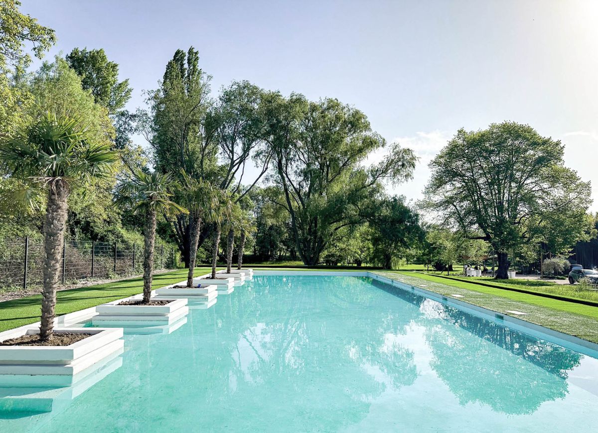 Rectangular pool with white stepped palm planters and manicured lawn at event venue