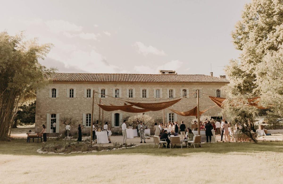 30 guests under rust-orange canopy with fairy lights at Provencal stone mas cocktail hour