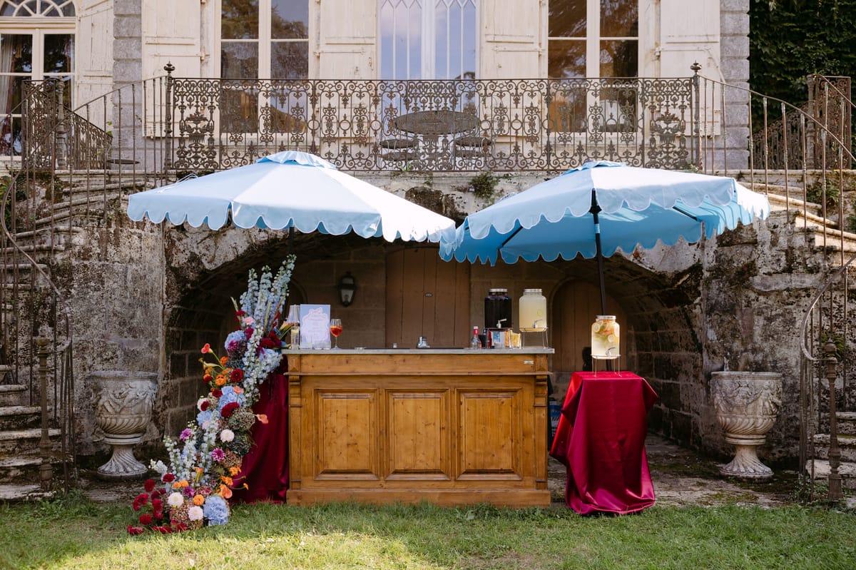 Poolside welcome drinks under sky-blue parasols in the gardens of Domaine de Perrotin for Rooa and Mark's wedding weekend