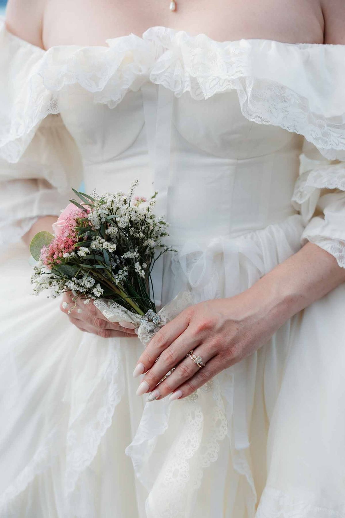 Bride holding dainty bouquet against vintage lace gown at Palace de Menthon Annecy