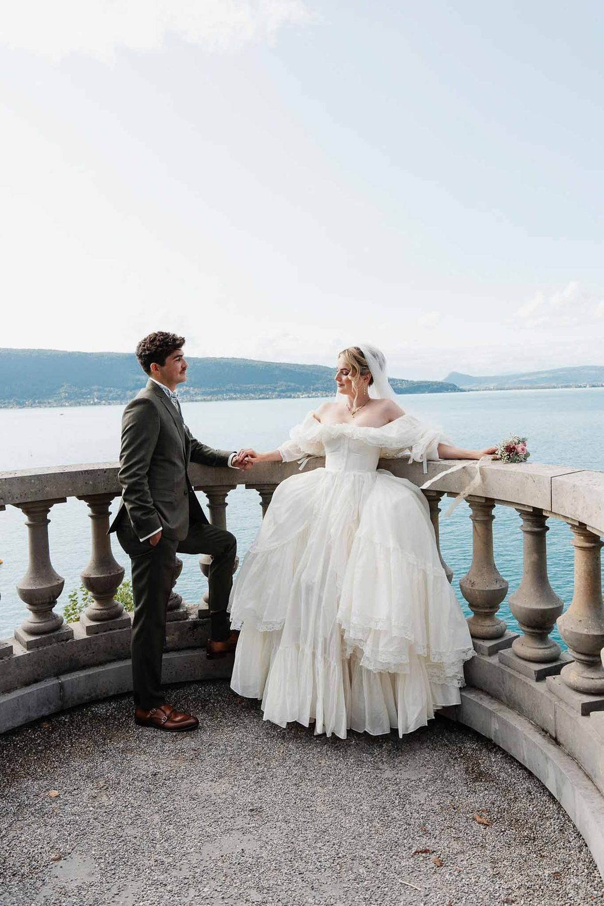Couple at stone balustrade with Lake Annecy and mountains at Palace de Menthon