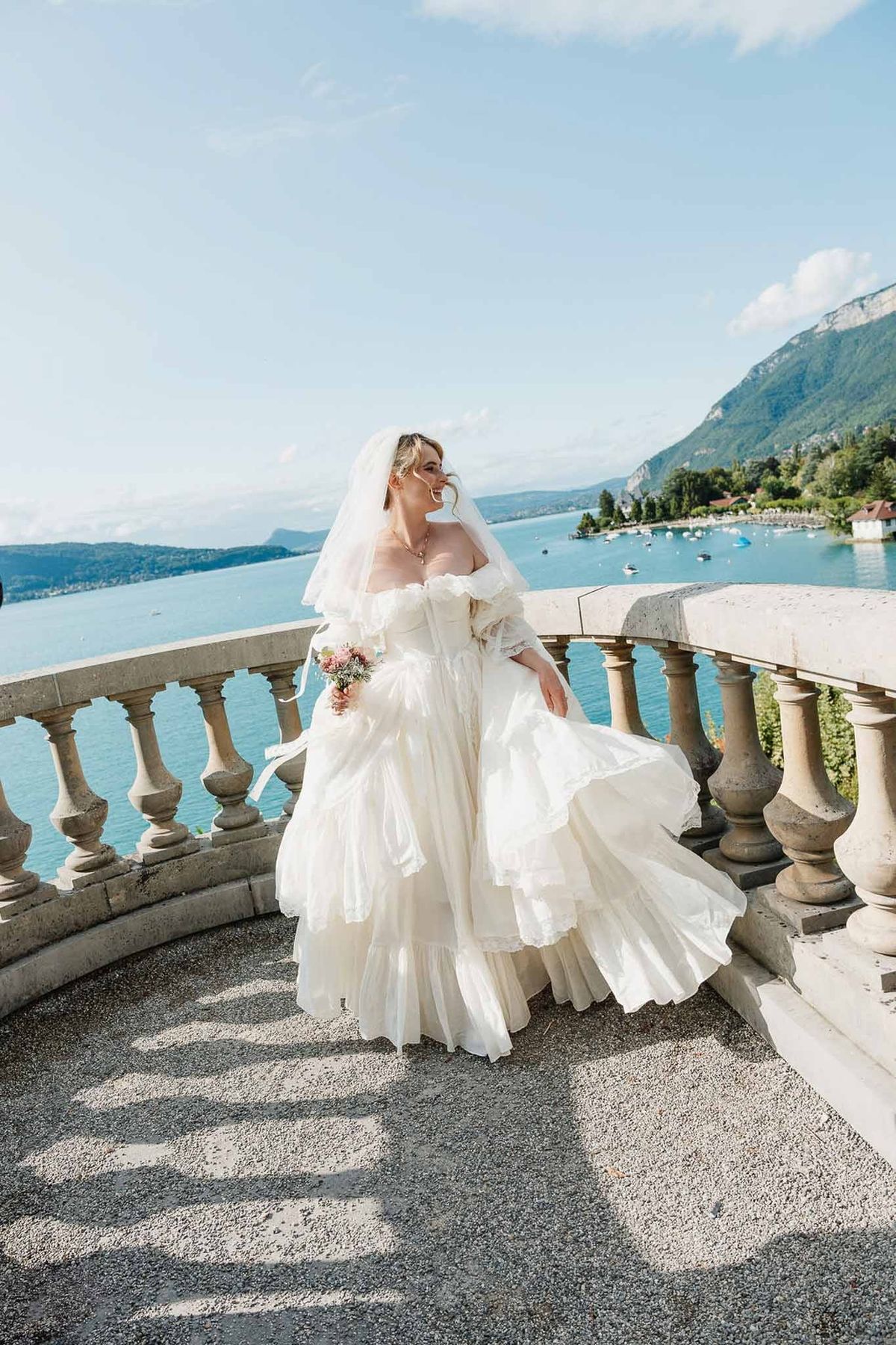 Bride in vintage gown overlooking Lake Annecy from terrace at Palace de Menthon