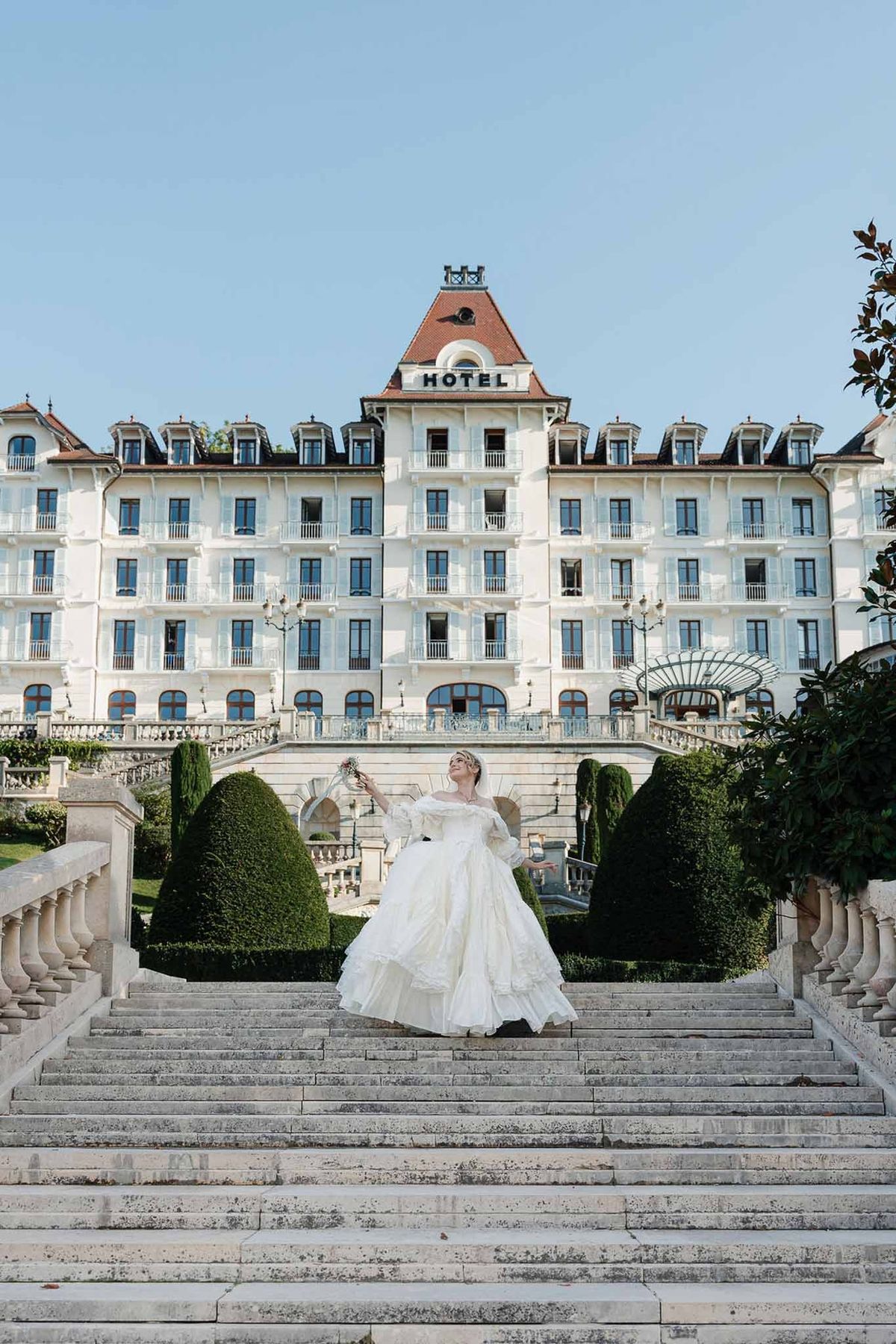 Bride on grand staircase with Belle Époque hotel façade at Palace de Menthon Annecy